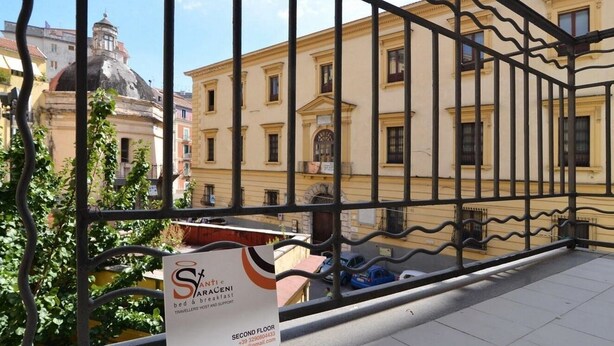 A balcony with a metal railing overlooking a building with a dome and a sign for 'St. Anthony's bed & breakfast' on the second floor. - Santi e Saraceni (Salerno)