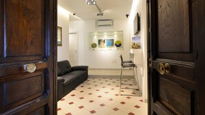 A hallway with a checkered floor, a black leather sofa, and a bar stool. - Santi e Saraceni (Salerno)