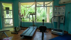 Un gimnasio con equipo de ejercicio, un ventanal grande y un cartel en la pared.