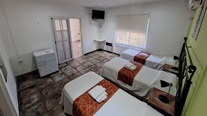 Una habitación de hotel con dos camas, un escritorio pequeño, un televisor y una ventana con vistas.