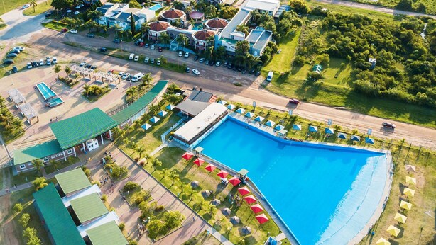 Vista aérea de un resort con una gran piscina, varias construcciones y un estacionamiento.