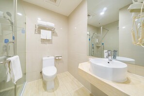 A modern bathroom with a glass-enclosed shower, a toilet, and a vanity with a sink and mirror. - Hanting Hotel (Shanghai)