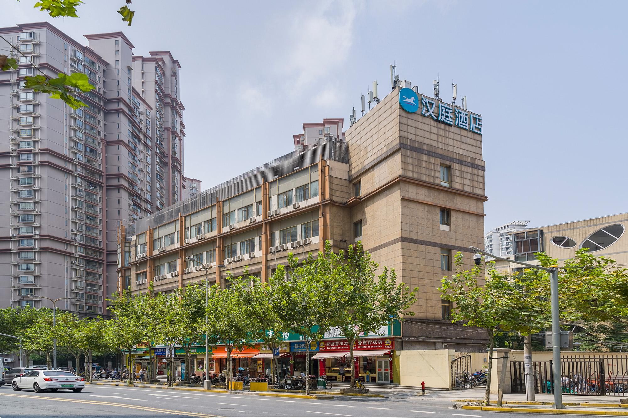 A hotel with multiple floors, a prominent sign, and a row of trees along the street.