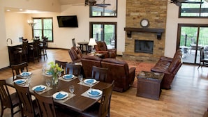 A spacious living room with a fireplace, leather sofas, and a dining area with a set table. - Hidden Meadows B&B (Stillwater)
