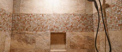 Un espace douche avec un mur décoré d’une mosaïque et une pomme de douche à main.
