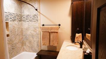 A bathroom with a bathtub, a shower, a sink, and a mirror.