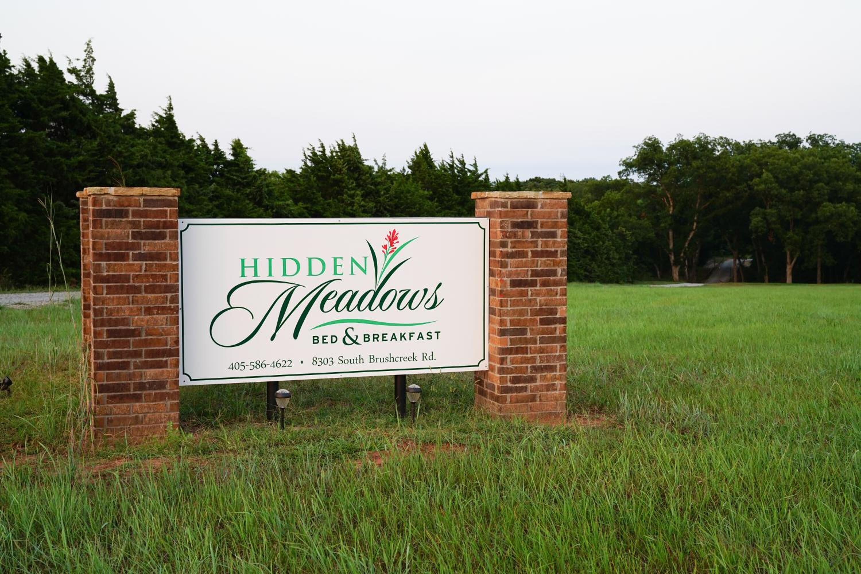 Placa indicativa do Bed & Breakfast Hidden Meadows, com informações de contato e endereço.