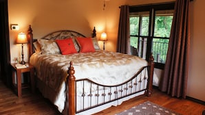 A bedroom with a large bed, two bedside lamps, a window with curtains, and a ceiling fan. - Hidden Meadows B&B (Stillwater)