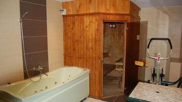 Un baño con bañera de madera, ducha e inodoro.