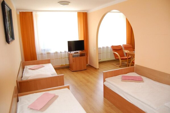 Ein Hotelzimmer mit zwei Betten, einem Fernseher, einem Schreibtisch und einem Sessel.