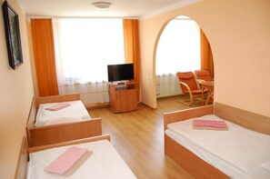 A hotel room with two beds, a television, a desk, and a chair.