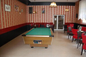 A billiards room with a pool table, red and black striped walls, and red chairs. - Hotel S Cupsk (Slupsk)