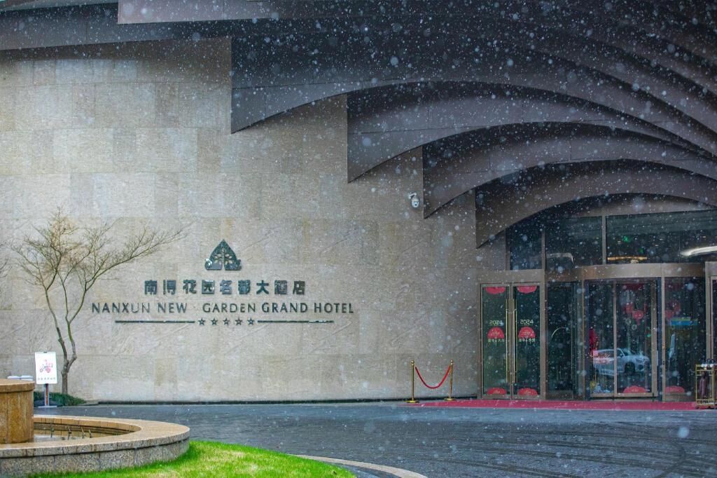 The exterior of Nanxun New Garden Grand Hotel with a stone facade and arched entrance.