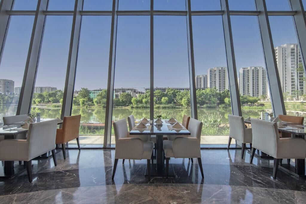 Un área de comedor con amplia vista a un lago y edificios.
