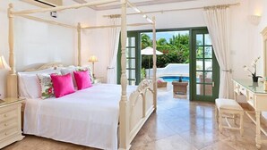 A four-poster bed with white bedding and pink pillows, a vanity with a mirror, and a view of a pool through an open door. - The Summer House, Sugar Hill Resort (Holetown)