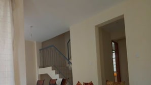 Eine Treppe, die zu einer oberen Etage führt, eine Tür zu einem Zimmer und ein Stuhl im Vordergrund.