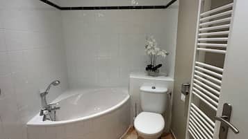 Een moderne badkamer met een vrijstaand bad, toilet en wastafel.