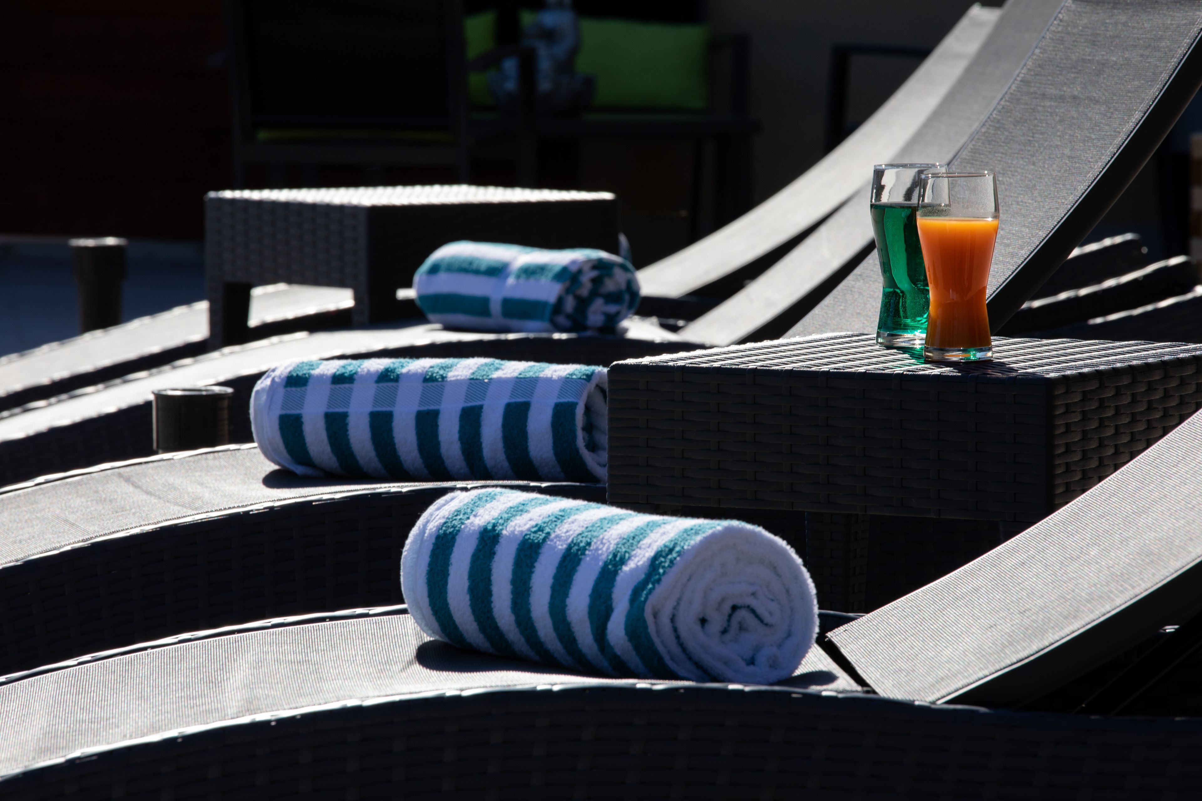 A sun lounger with a rolled towel and a glass of orange juice.