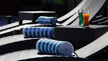 A sun lounger with a rolled towel and a glass of orange juice.