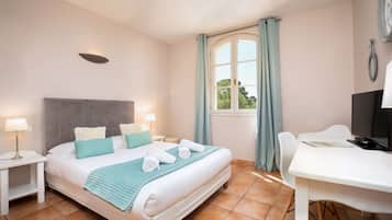 A bedroom with a bed, bedside tables, a desk, and a window with curtains.