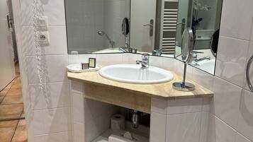 Un baño con lavamanos, espejo, toallero y secador de pelo montado en la pared.