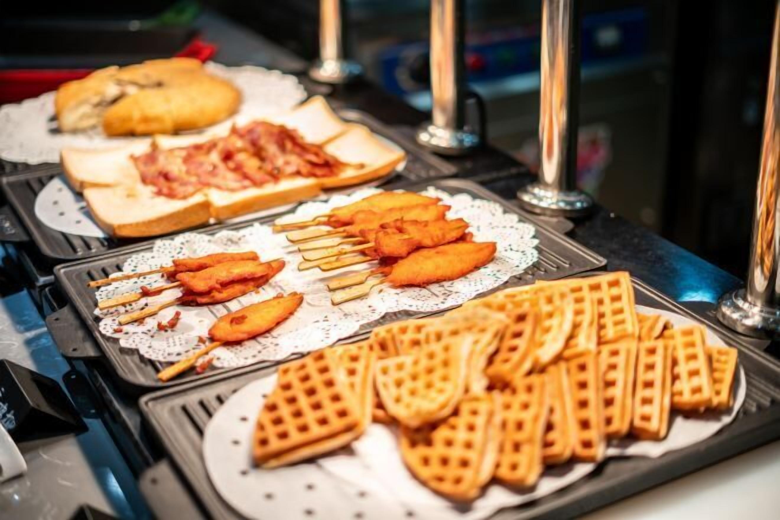 A buffet with various food items including sandwiches, fried fish, and waffles.
