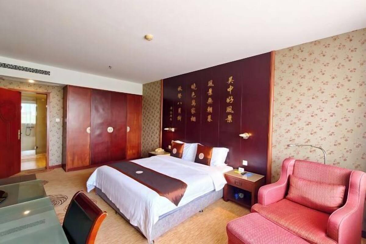 A hotel room with a bed, a desk, a chair, and a wardrobe.