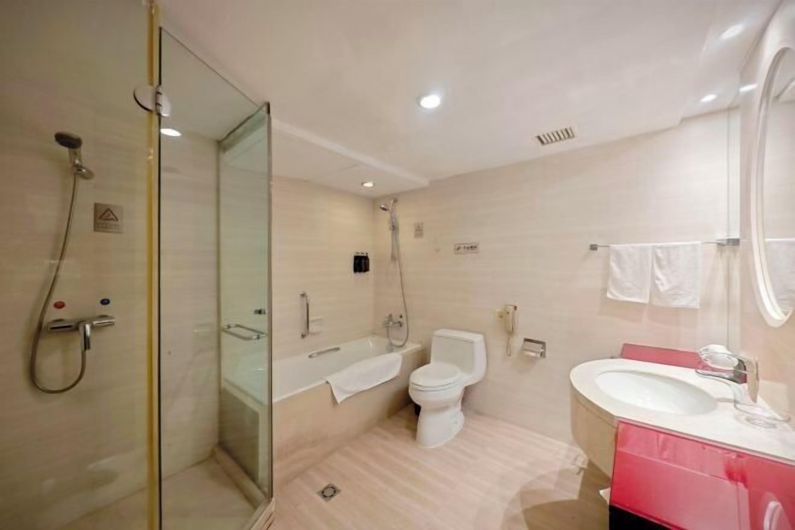 A bathroom with a glass-enclosed shower, a toilet, a bathtub, and a sink with a mirror.
