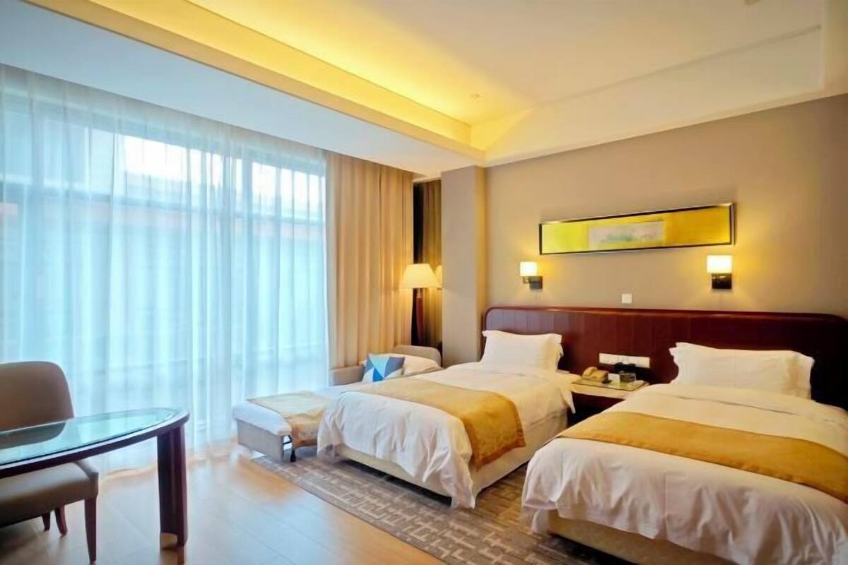 A hotel room with two beds, a desk, and a chair.