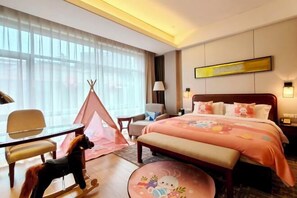 A hotel room with a bed, a desk, a chair, a small table, a bench, a tent, and a wall-mounted lamp.