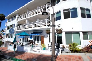 A two-story building with a balcony, outdoor seating, and a sign indicating it is a hotel. - Sea Horse Resort (San Clemente)