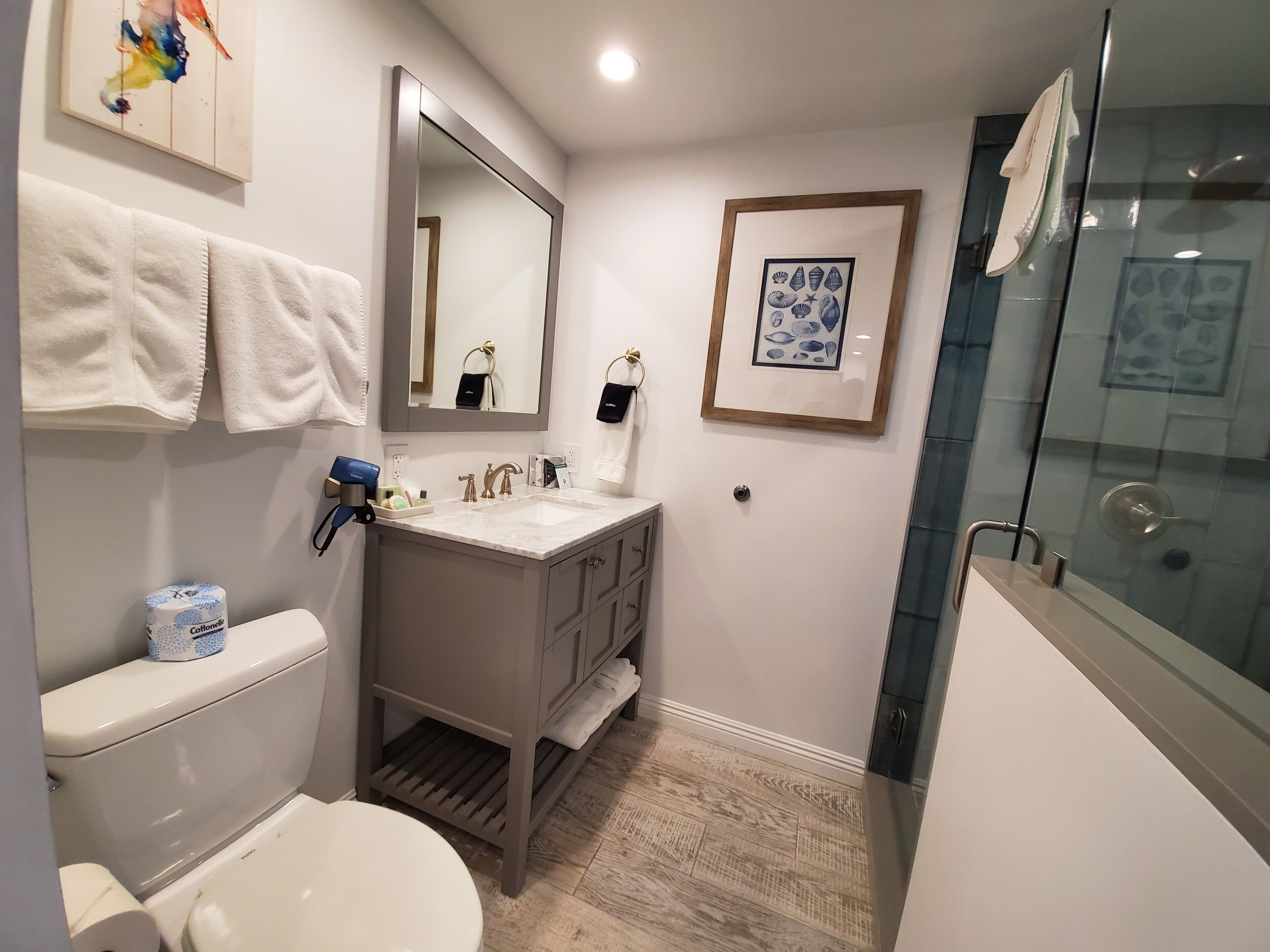 A bathroom with a toilet, sink, mirror, and shower.