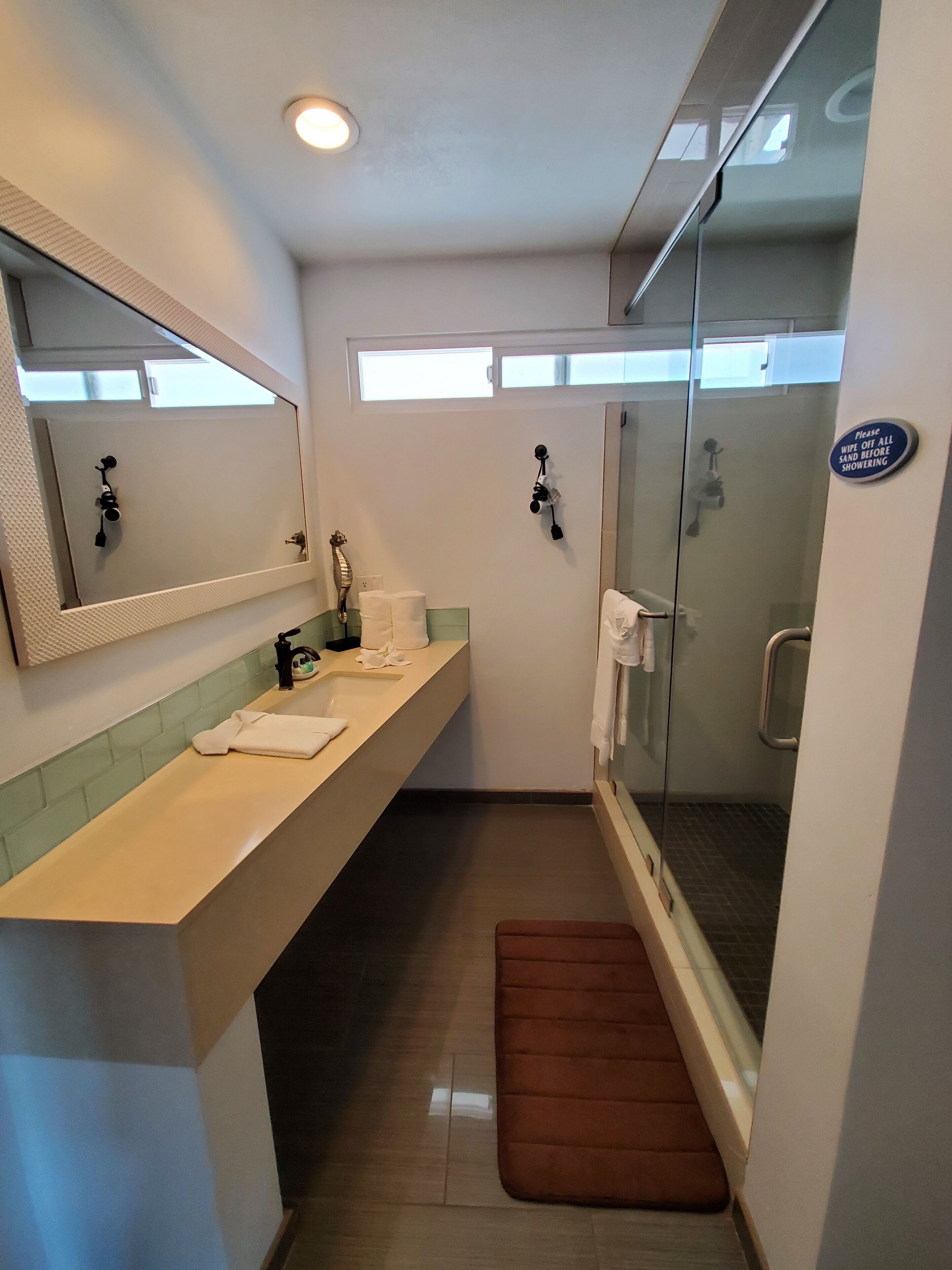 A bathroom with a sink, mirror, towel rack, and a glass shower stall.