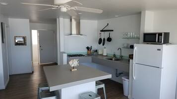 A modern kitchen with a central island, a built-in microwave, and a refrigerator.