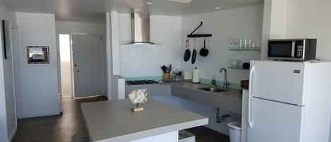 Une cuisine moderne dotée d’un îlot central, d’un four à micro-ondes encastré et d’un réfrigérateur.
