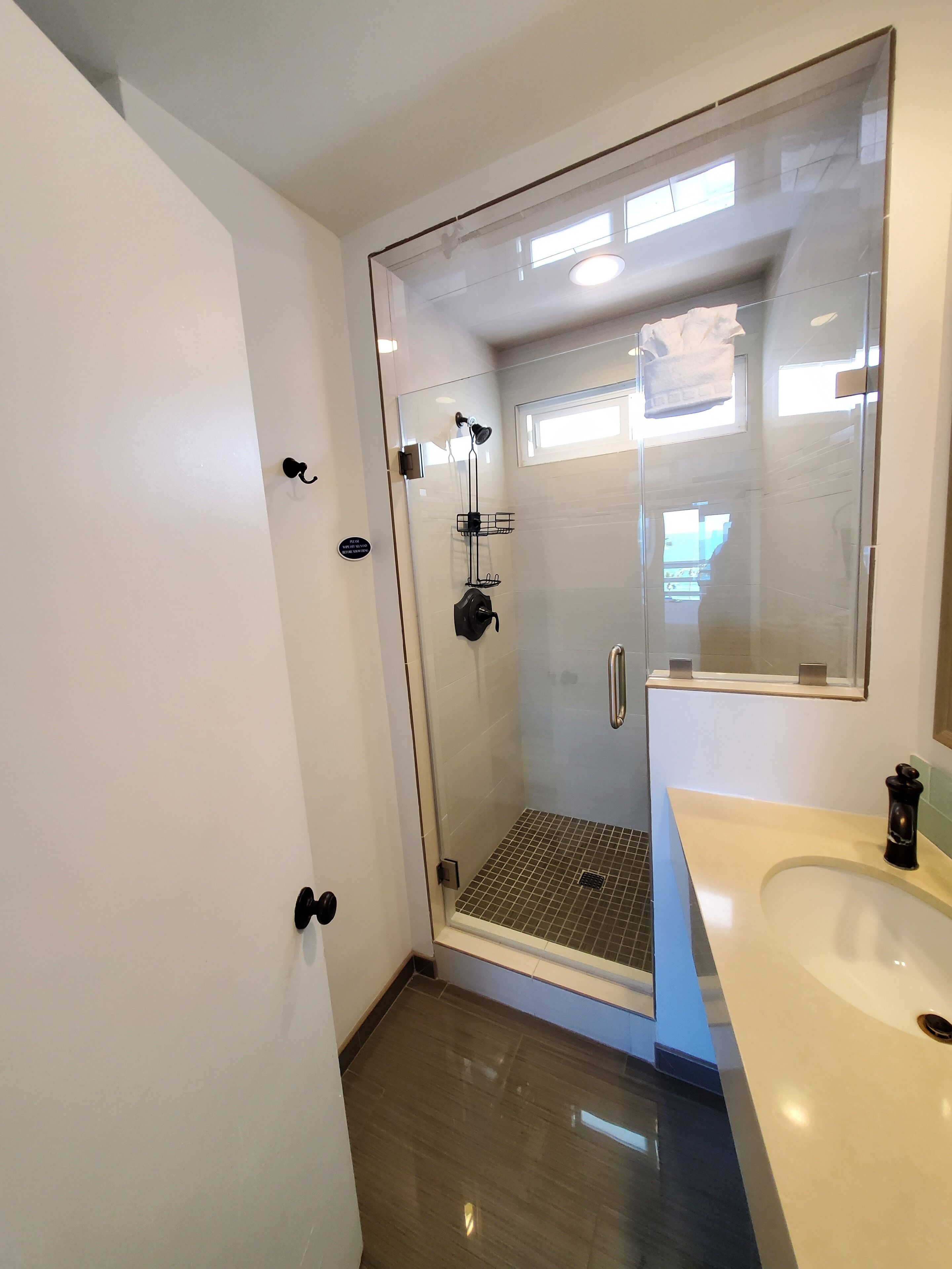 Une salle de bain moderne avec une douche à parois de verre, un lavabo blanc et un grand miroir.
