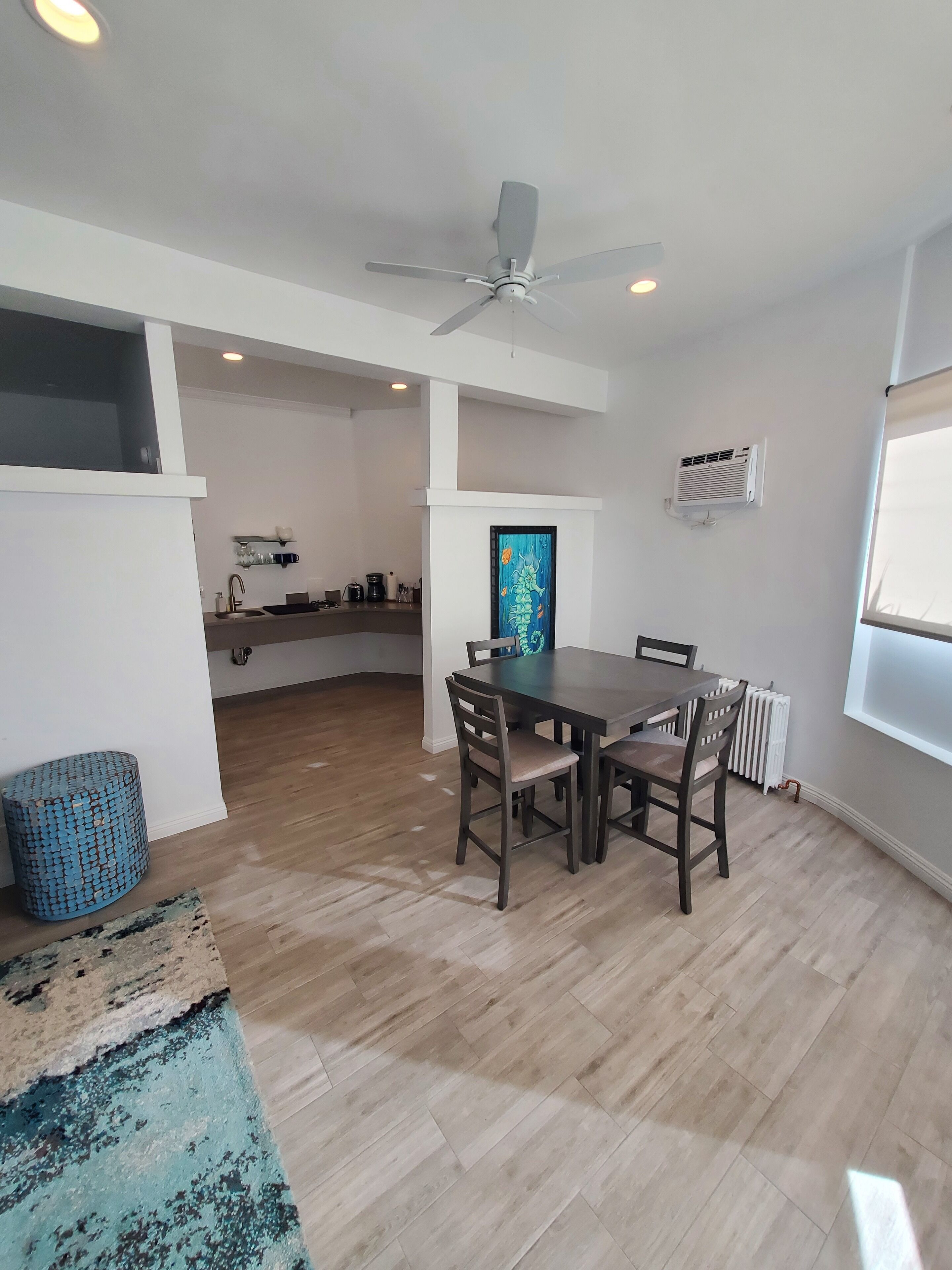 A spacious dining area with a large table and chairs, a ceiling fan, and a view of the kitchen in the background.