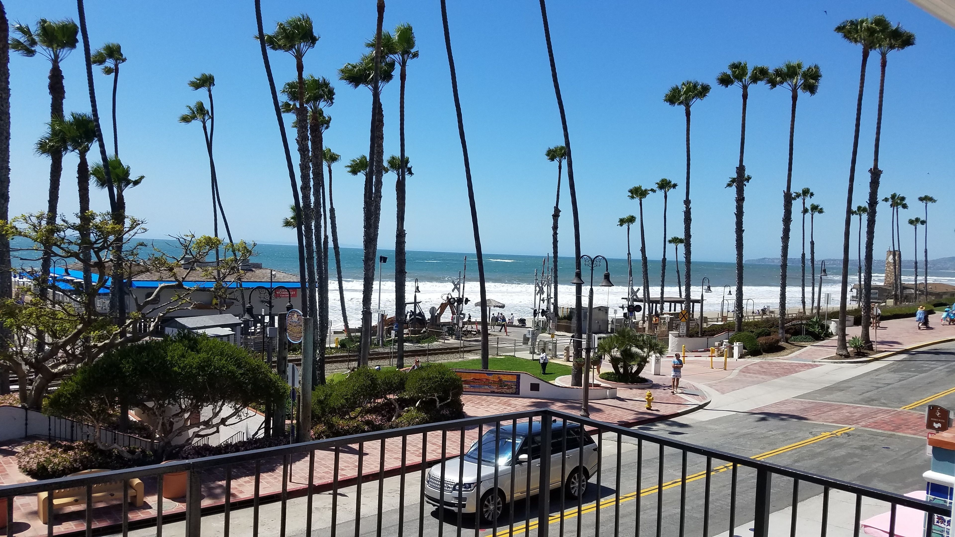 Une vue sur la côte, avec des palmiers, une plage et un espace de stationnement.