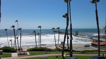 A beach view with palm trees, a pier, and a lifeguard tower.