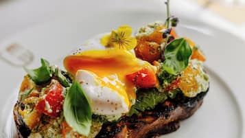 Un plato con pan tostado cubierto de verduras, tomates y un huevo pochado.
