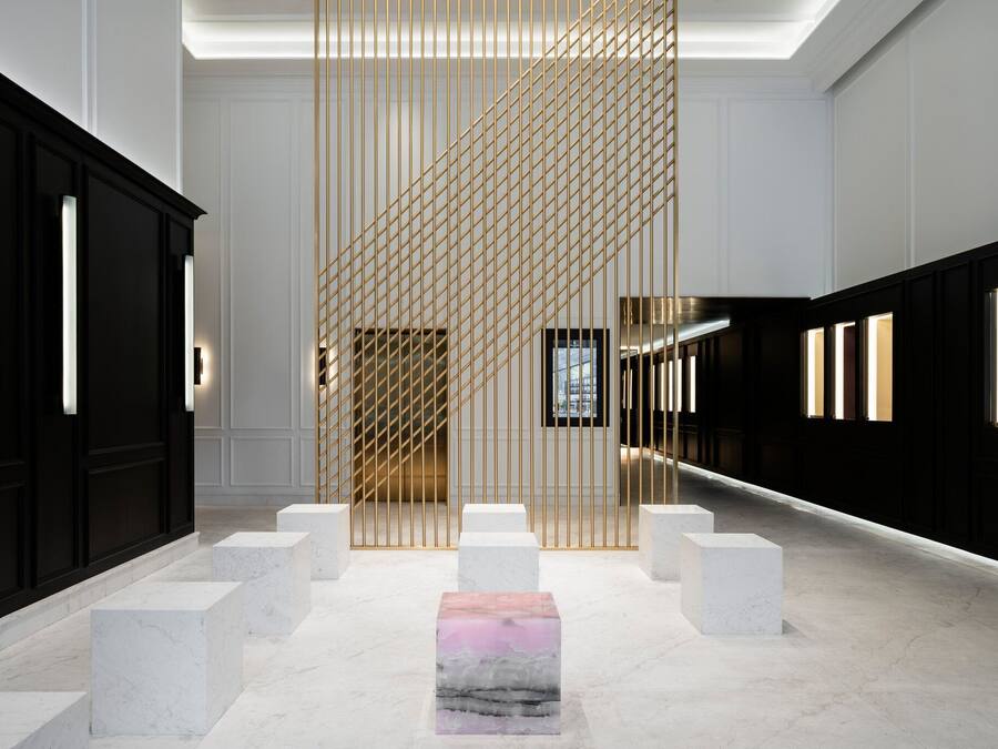 A modern interior with a central walkway flanked by white marble blocks and a patterned wall.
