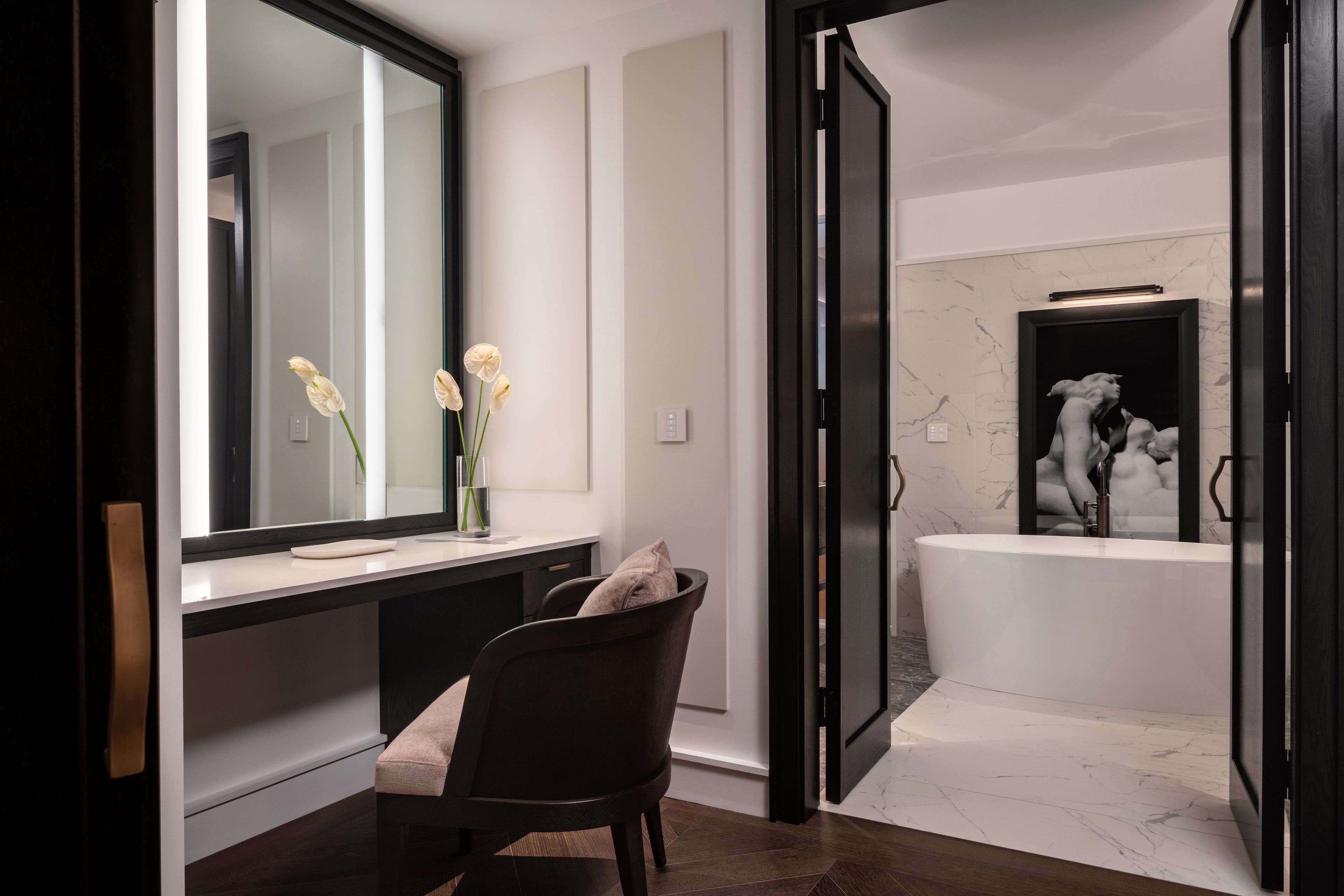 Un baño moderno con un espejo grande, una bañera y una silla.