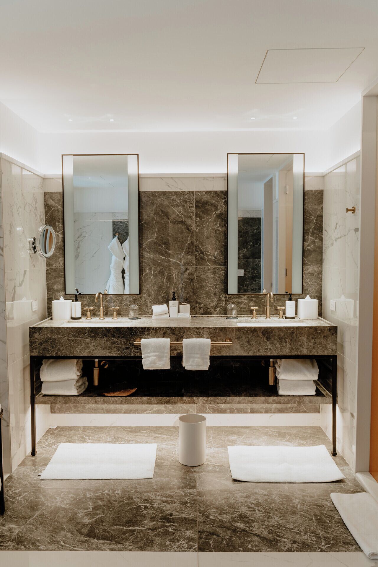 Un baño moderno con dos lavamanos, encimeras de mármol y un espejo grande.