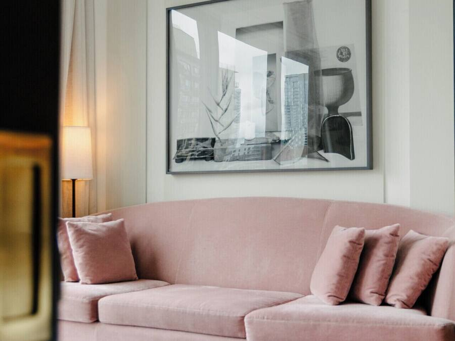 A modern living room with a pink sofa, a round coffee table, and a large framed artwork on the wall.