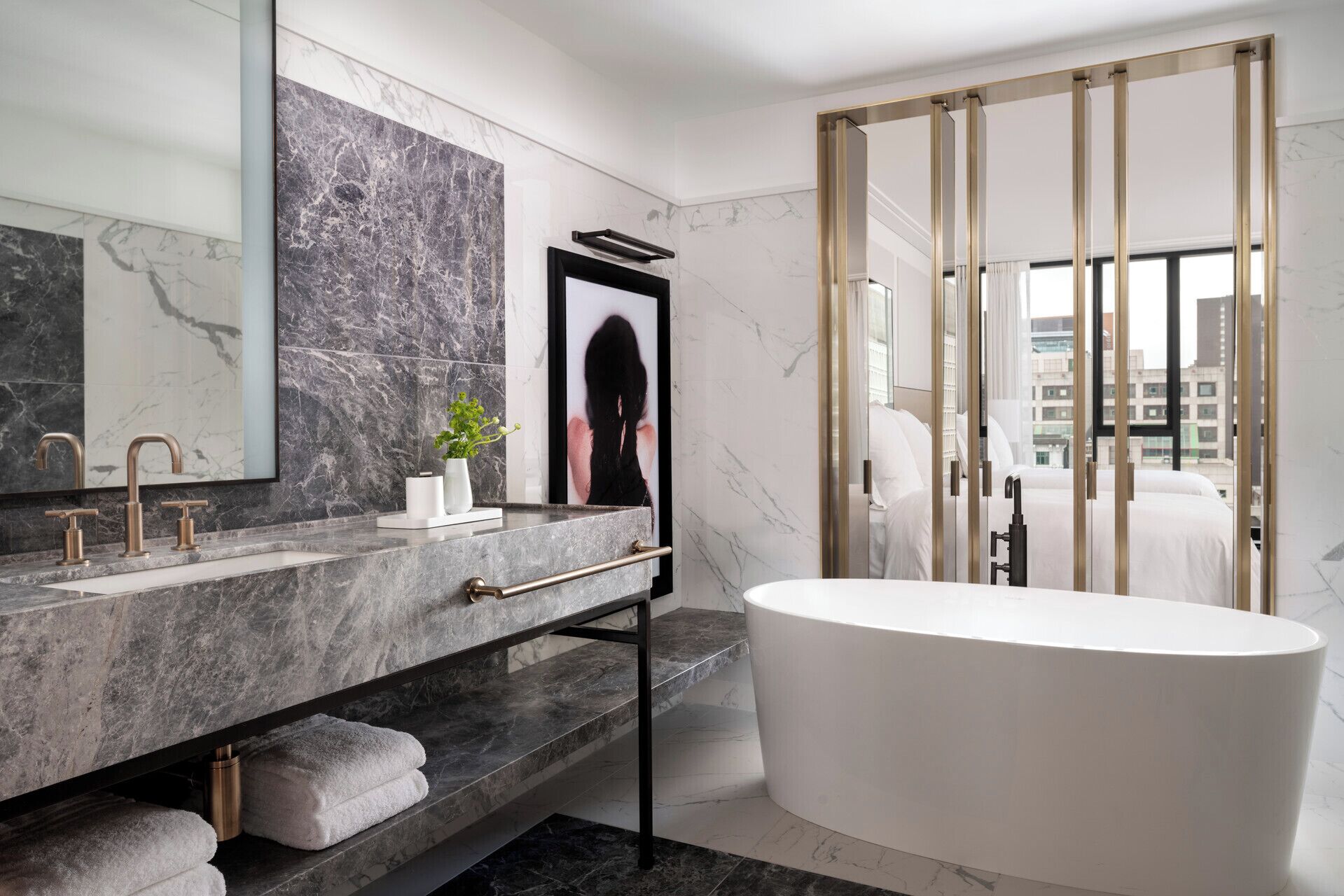 A modern bathroom with a marble vanity, a freestanding bathtub, and a large mirror.