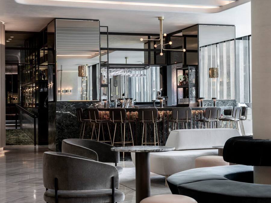 Uma área de bar moderna com assentos e uma escada que leva a um mezanino.