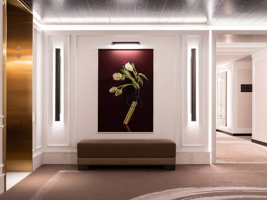Un vestíbulo moderno con un banco, una obra de arte enmarcada de flores y un mostrador de recepción.