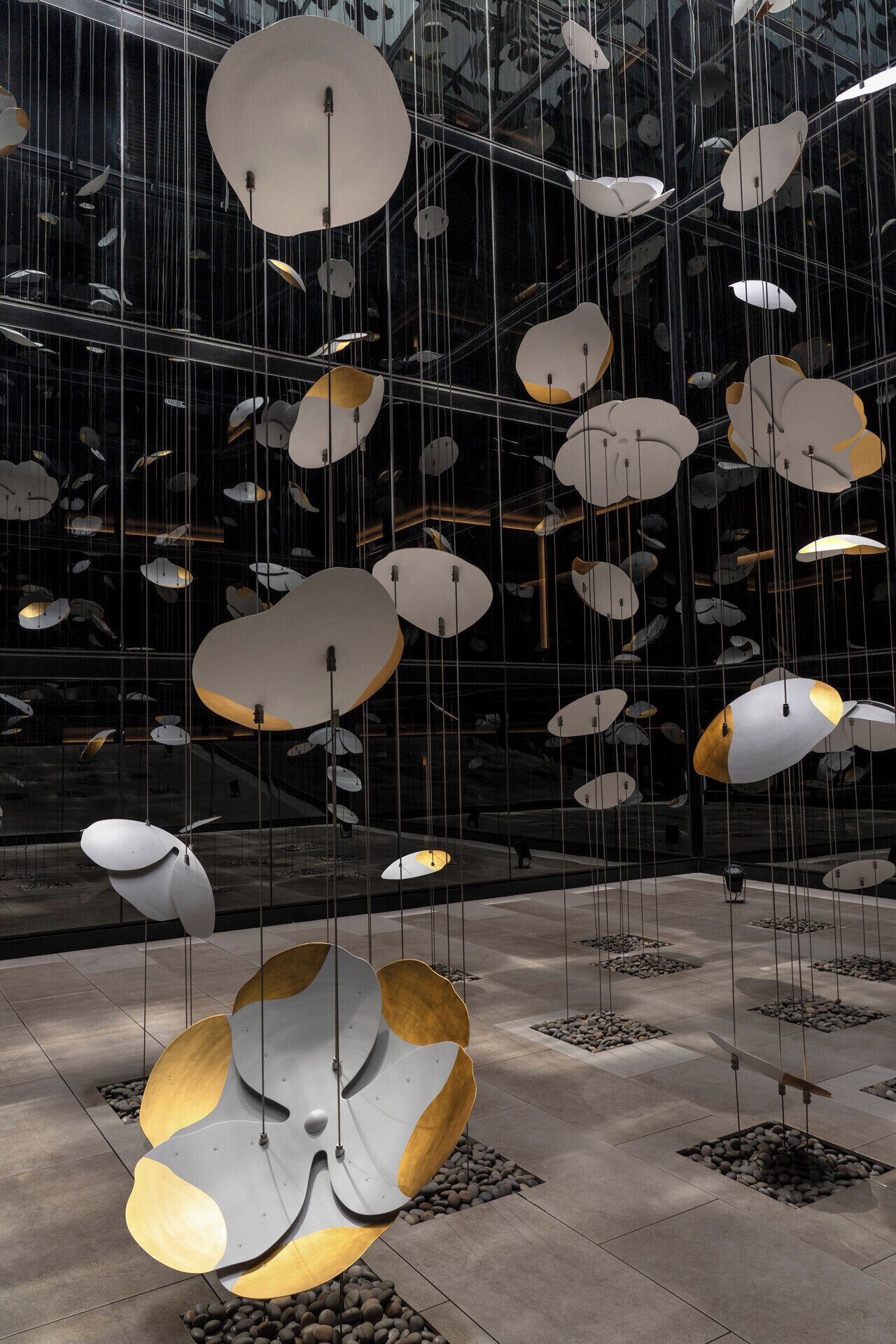 A modern interior with hanging spherical light fixtures and a reflective glass wall.