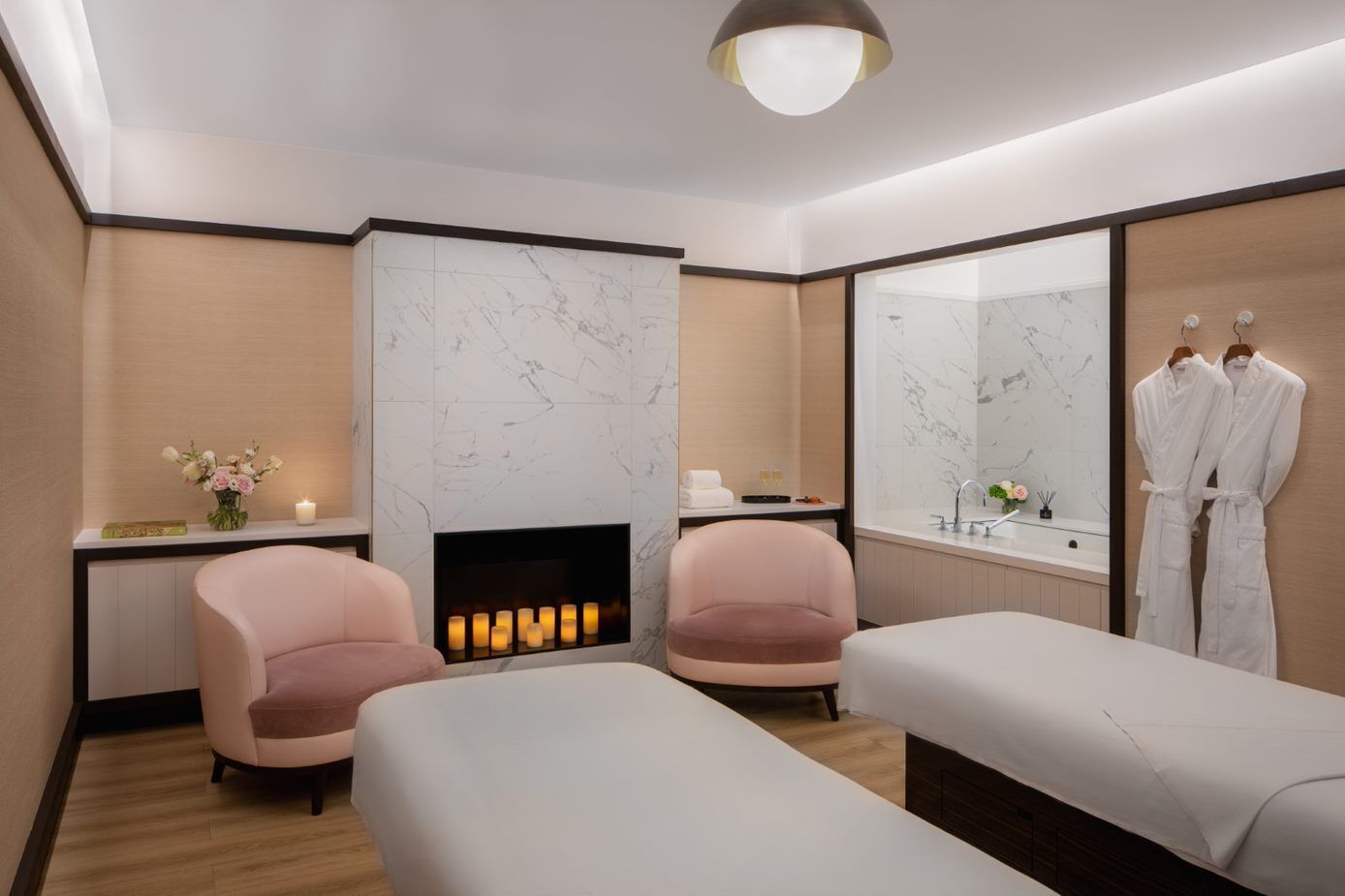 Un moderno spa con dos camillas de masaje, una chimenea y un espejo grande.