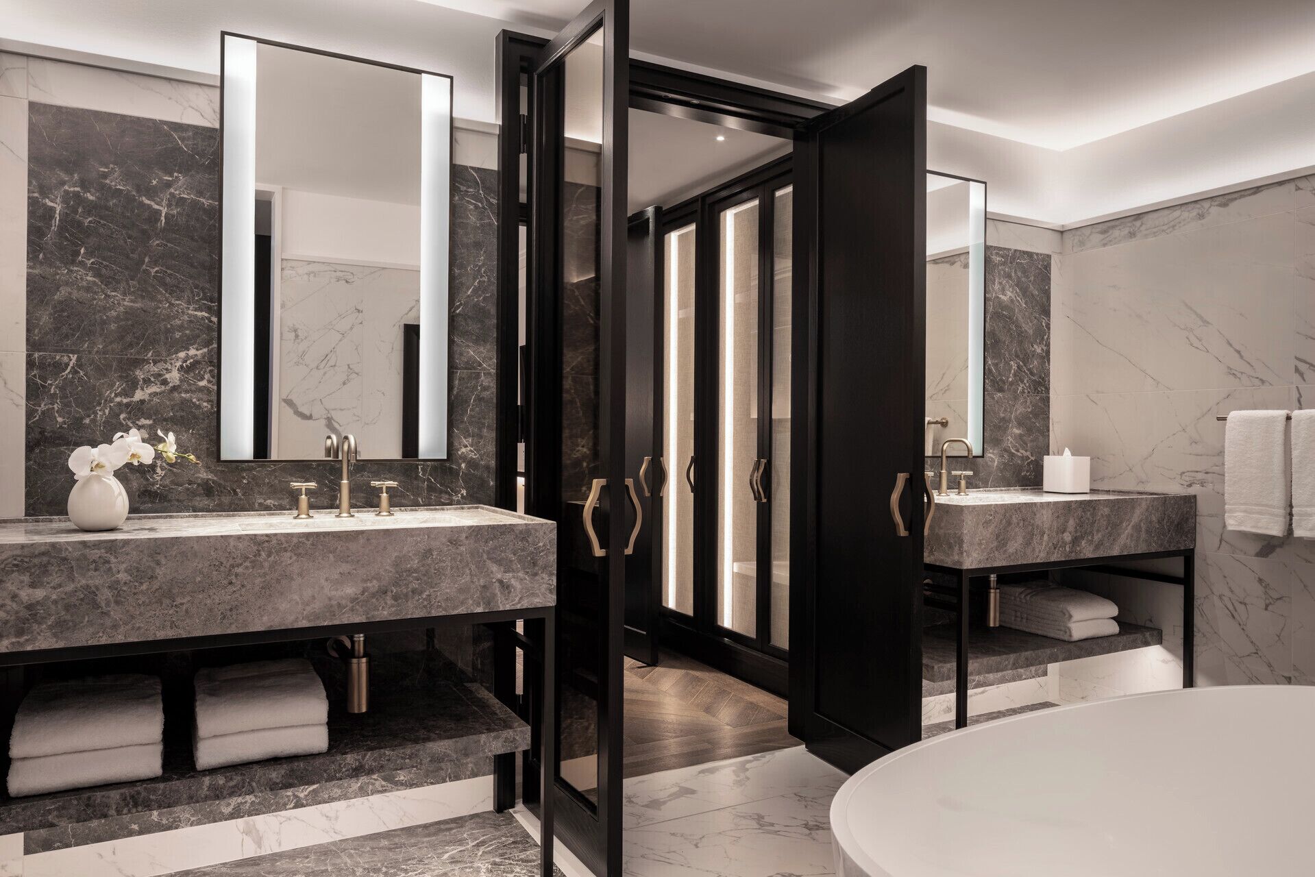Une salle de bain moderne avec deux lavabos, un grand miroir et une baignoire.